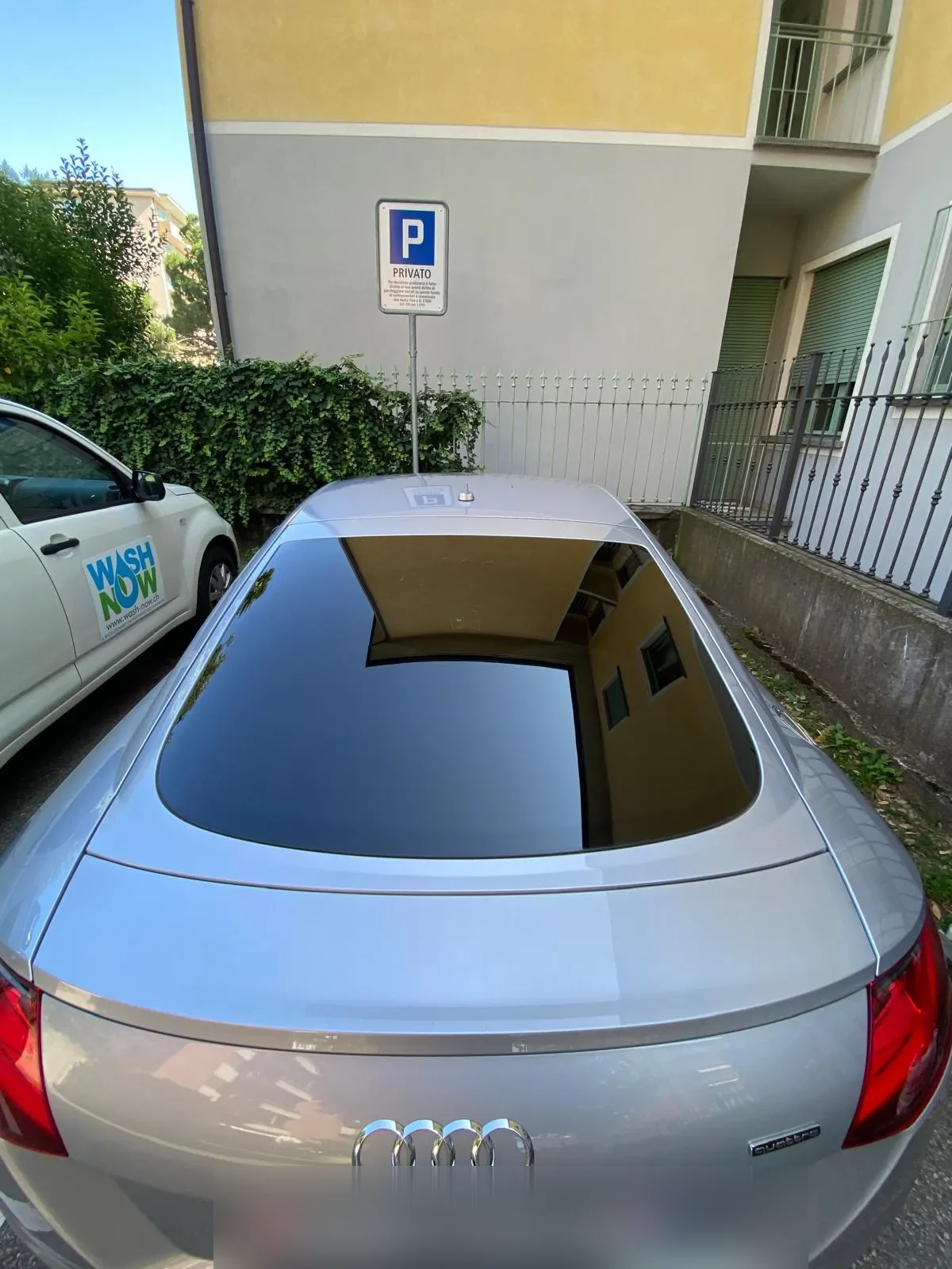 Audi TT Quattro grigia con tetto lucido e van Wash Now sullo sfondo